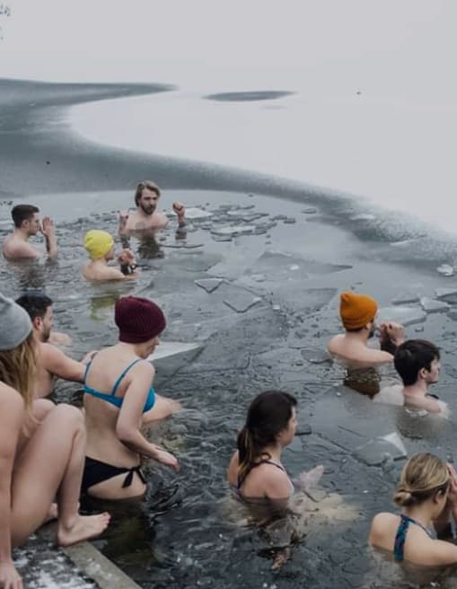 A group breathing together on the shore before going into a Berlin lake