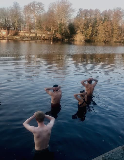 A group breathing together on the shore before going into a Berlin lake